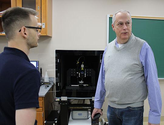 two men standing in front of a piece of equipment